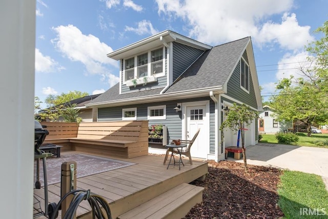 back of property featuring driveway, a shingled roof, and a wooden deck