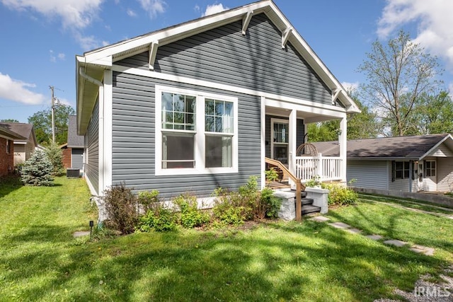 rear view of property with a lawn, cooling unit, and a porch
