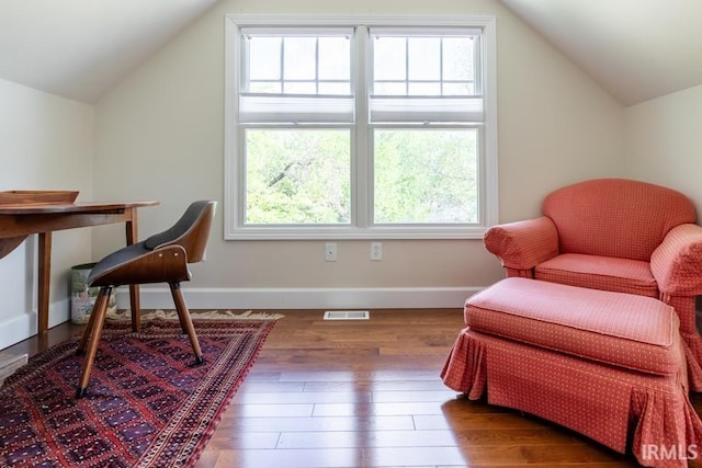 living area with hardwood / wood-style floors, plenty of natural light, lofted ceiling, and visible vents