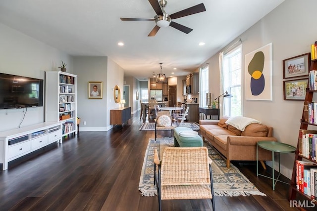 living room featuring dark wood-type flooring, baseboards, recessed lighting, and ceiling fan with notable chandelier