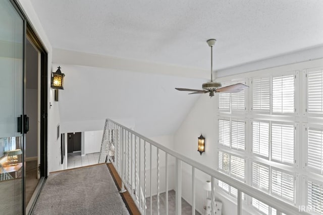 hallway with an upstairs landing, carpet, and a textured ceiling