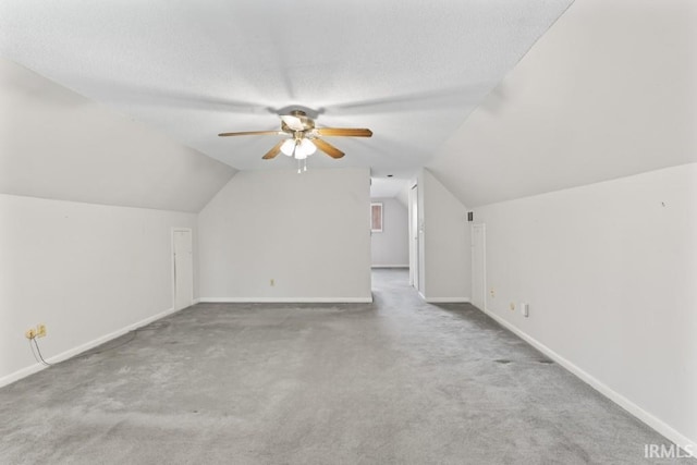 bonus room with carpet flooring, a textured ceiling, vaulted ceiling, and a ceiling fan