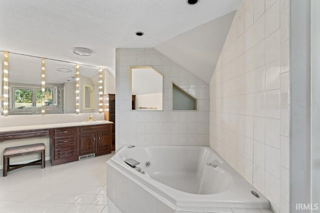 full bath featuring vanity, a whirlpool tub, lofted ceiling, visible vents, and tile walls