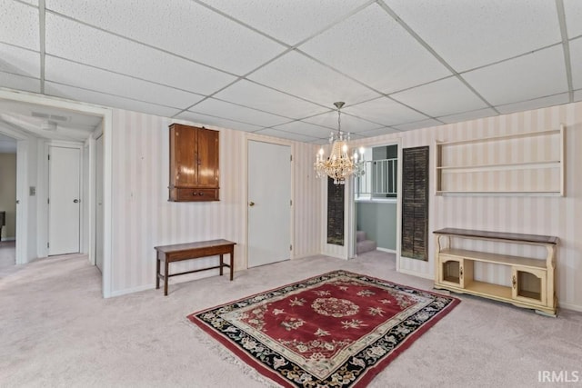 interior space with baseboards, an inviting chandelier, a paneled ceiling, and carpet