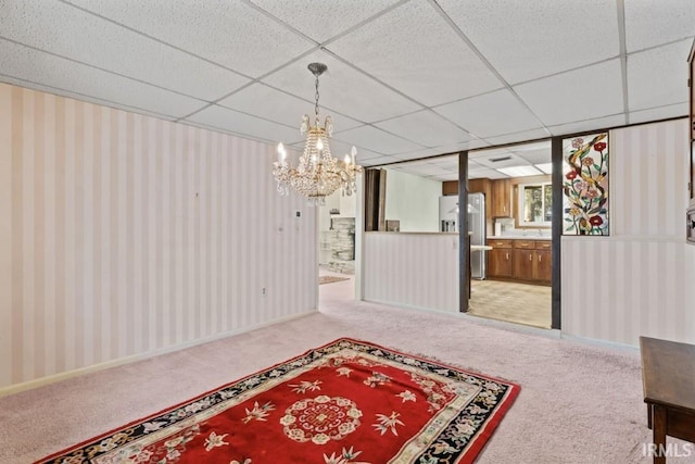 dining space featuring light carpet, a paneled ceiling, and a chandelier
