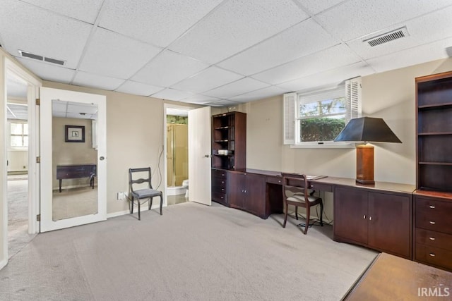 home office with visible vents, a drop ceiling, and carpet