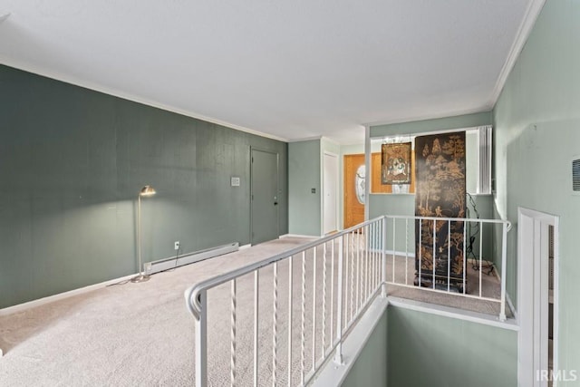 corridor featuring carpet flooring, an upstairs landing, a baseboard heating unit, and ornamental molding