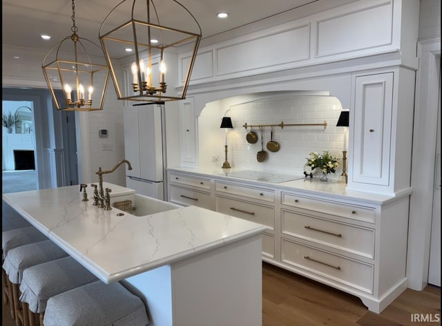 kitchen with white appliances, white cabinetry, a sink, dark wood-style floors, and a notable chandelier