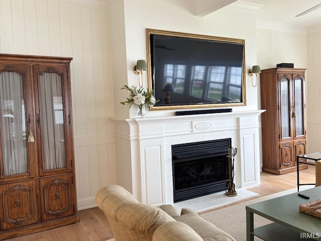 living room featuring light wood-style flooring, crown molding, and a fireplace