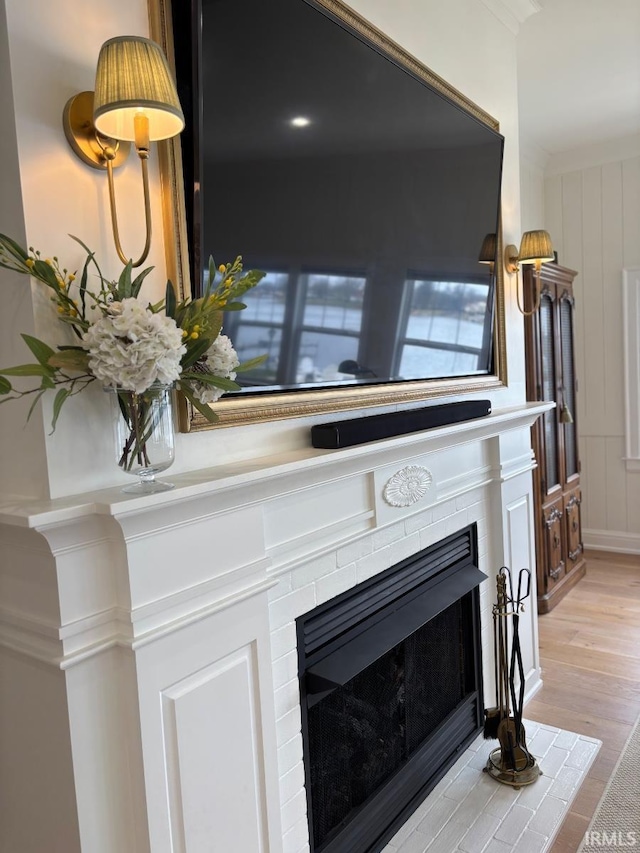 interior details with wood finished floors, a tile fireplace, and a decorative wall