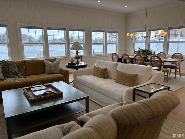 living area featuring recessed lighting, an inviting chandelier, ornamental molding, a water view, and wood finished floors