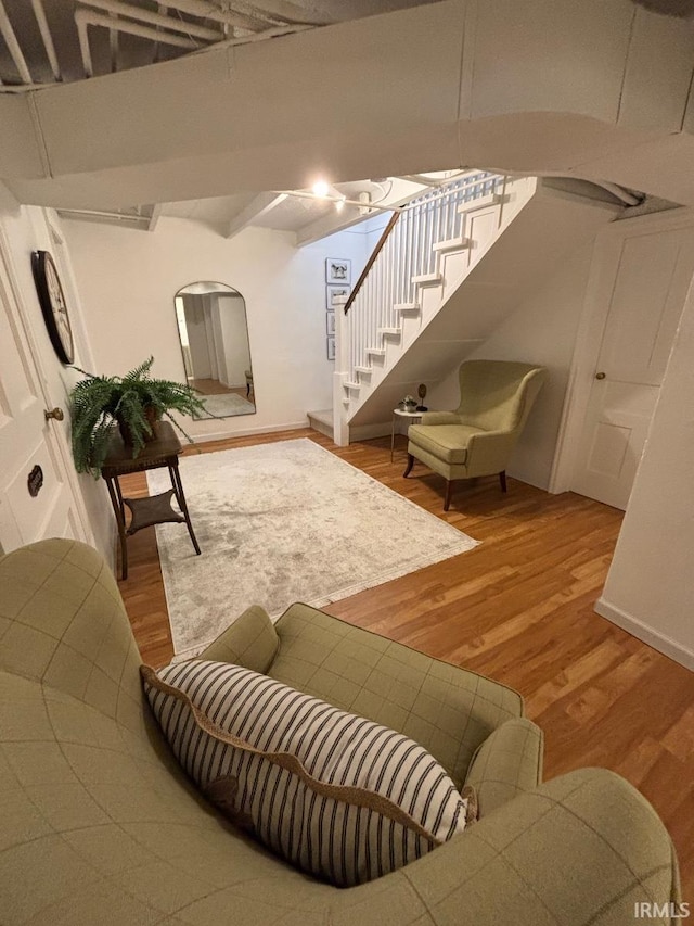 living area with baseboards, wood finished floors, and stairway