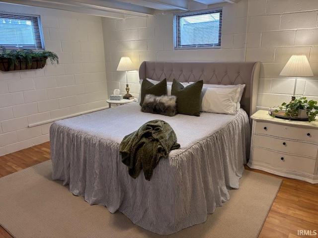 bedroom with concrete block wall and light wood-type flooring