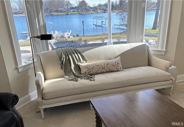 living area featuring baseboards, a water view, and carpet floors