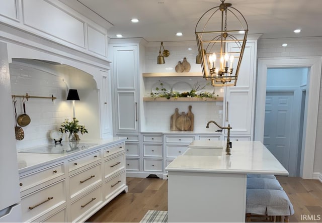 kitchen featuring a notable chandelier, light countertops, a sink, black electric stovetop, and dark wood-type flooring