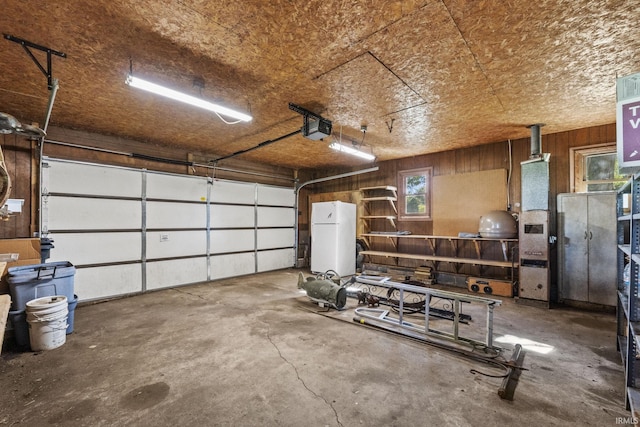 7990 S 150 E, Wolcottville, IN 46795 - garage featuring a garage door opener, wood walls, and freestanding refrigerator