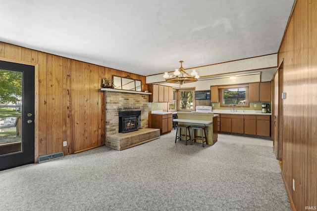 7990 S 150 E, Wolcottville, IN 46795 - living room featuring wood walls, light colored carpet, visible vents, a brick fireplace, and a notable chandelier