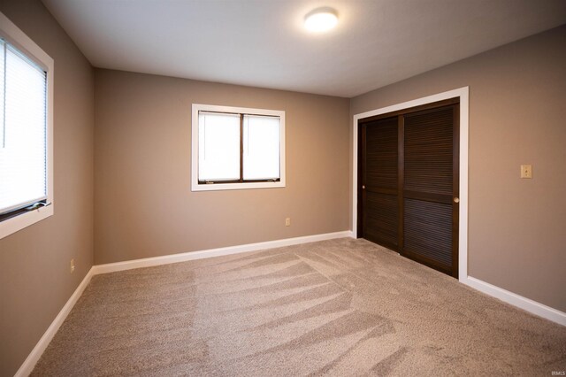 unfurnished bedroom with baseboards, carpet flooring, and a closet
