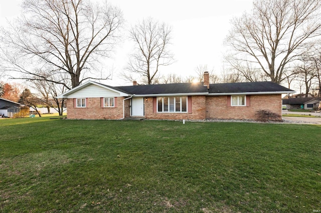 ranch-style house with brick siding, a chimney, and a front lawn
