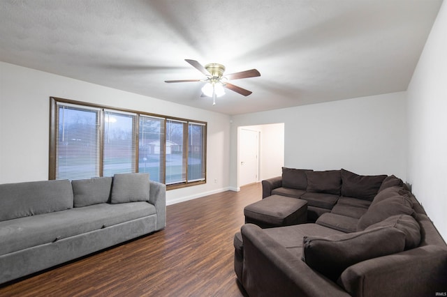 living area featuring dark wood finished floors, baseboards, and a ceiling fan