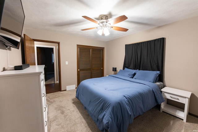 bedroom with a closet, visible vents, baseboards, ceiling fan, and light carpet