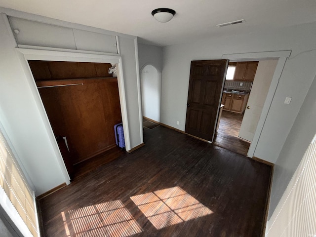 1116 Stanley Ave, Evansville, IN 47711 - unfurnished bedroom featuring a closet, visible vents, baseboards, arched walkways, and dark wood-type flooring