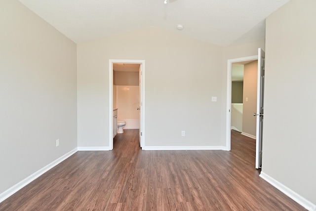 3843 S Bushmill Dr, Bloomington, IN 47403 - unfurnished bedroom featuring dark wood finished floors, baseboards, lofted ceiling, and ensuite bathroom