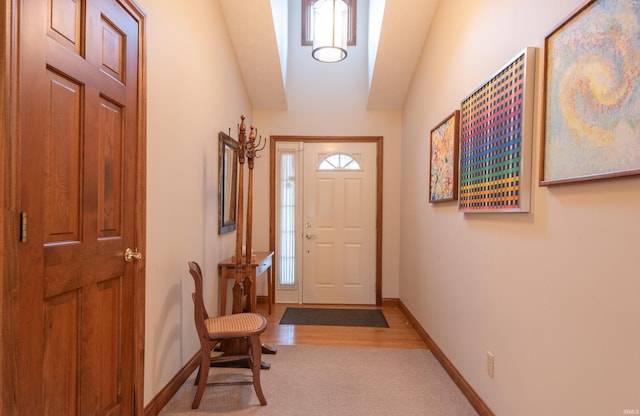 foyer featuring plenty of natural light, baseboards, lofted ceiling, and light colored carpet