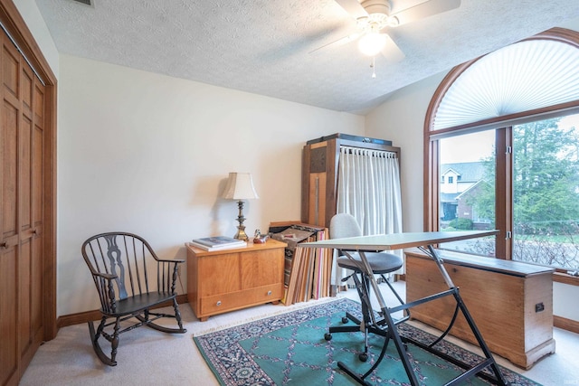 office featuring light carpet, baseboards, ceiling fan, and a textured ceiling