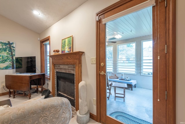 living area featuring baseboards, vaulted ceiling, and a fireplace