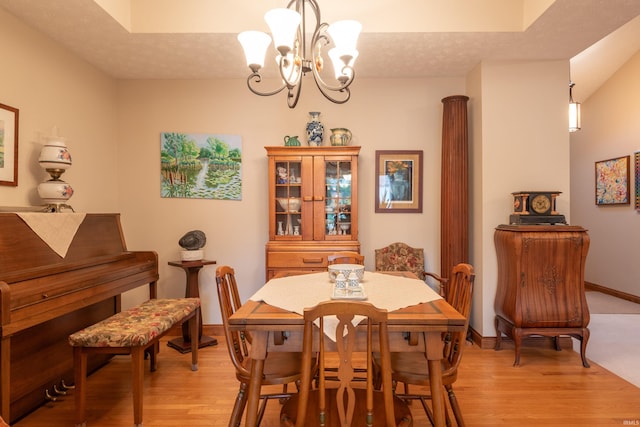 dining space featuring an inviting chandelier, baseboards, light wood-style floors, and a textured ceiling