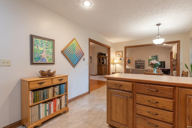 kitchen featuring hanging light fixtures, brown cabinets, light countertops, and a textured ceiling