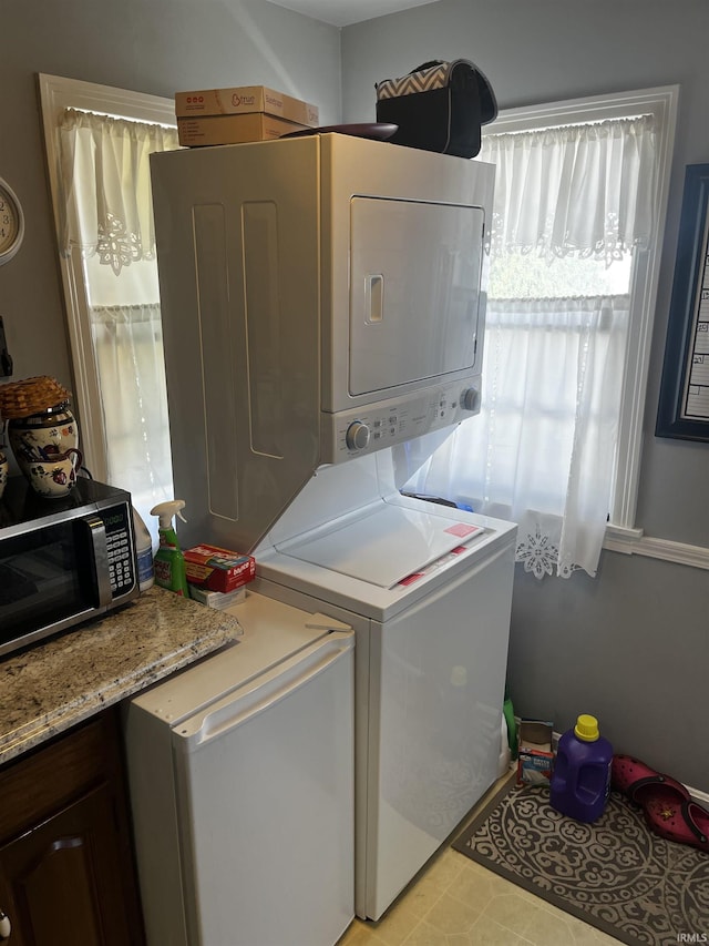 washroom featuring stacked washer and clothes dryer and laundry area