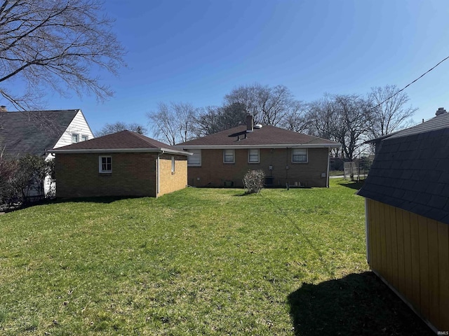 rear view of property featuring brick siding, an outbuilding, and a lawn