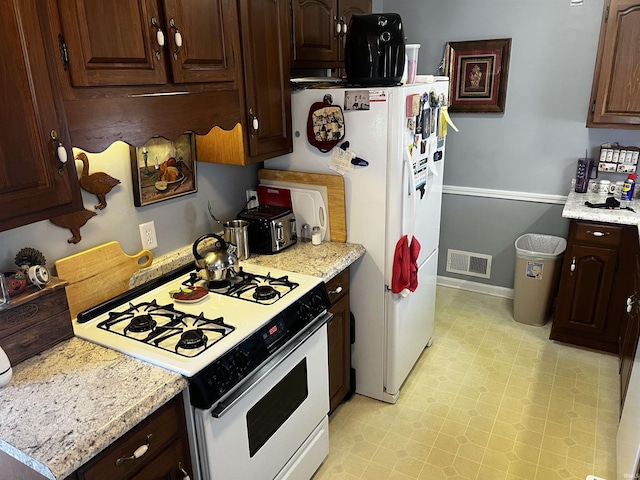 kitchen with visible vents, white appliances, baseboards, dark brown cabinets, and light floors