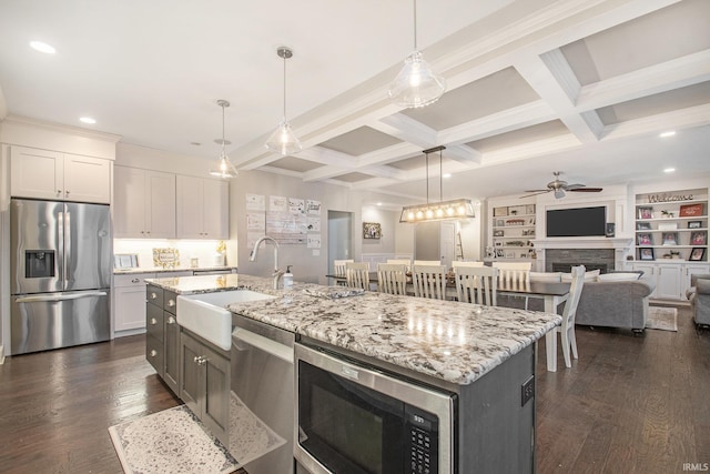 kitchen with ceiling fan, beam ceiling, appliances with stainless steel finishes, a sink, and dark wood-style floors