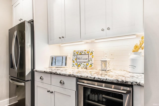kitchen with tasteful backsplash, stainless steel refrigerator with ice dispenser, light stone counters, beverage cooler, and white cabinets