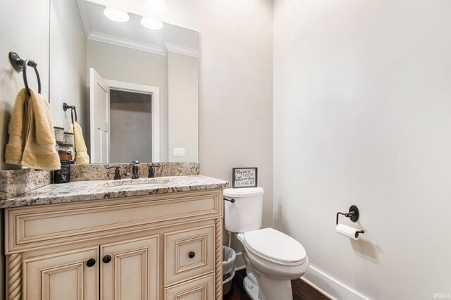 bathroom featuring toilet, vanity, crown molding, and baseboards
