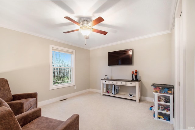 sitting room with ornamental molding, baseboards, carpet floors, visible vents, and ceiling fan