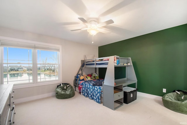 carpeted bedroom featuring a ceiling fan, a water view, and baseboards