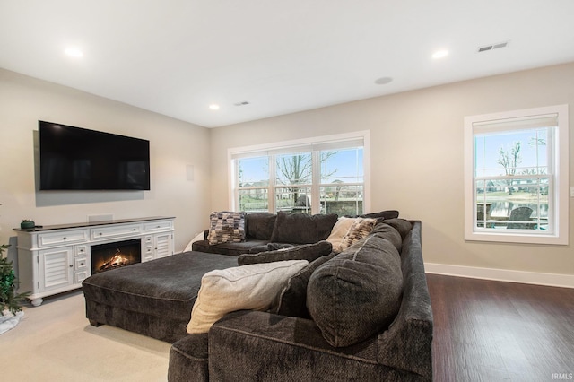 living room with visible vents, baseboards, wood finished floors, recessed lighting, and a lit fireplace