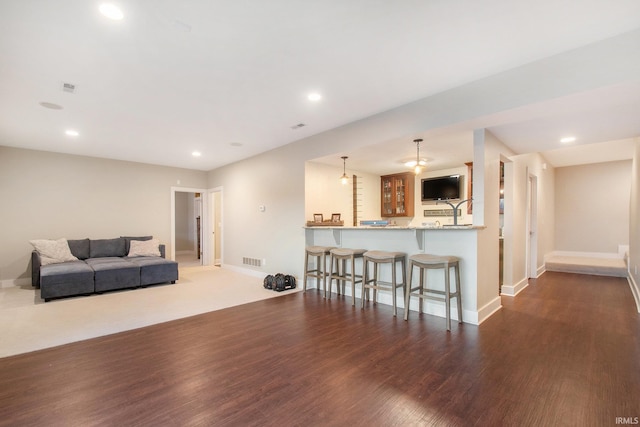 living area with baseboards, wood finished floors, and recessed lighting