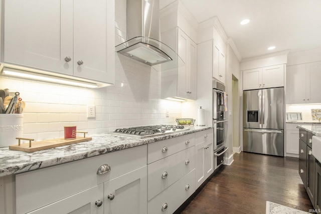 kitchen featuring dark wood finished floors, backsplash, wall chimney range hood, light stone countertops, and appliances with stainless steel finishes