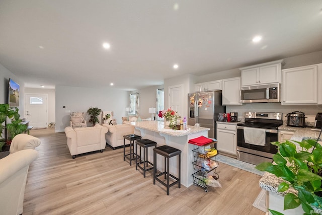 2751 Sand Hollow Dr, Lebanon, IN 46052 - kitchen featuring open floor plan, a kitchen bar, a center island, stainless steel appliances, and light wood finished floors