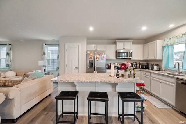 2751 Sand Hollow Dr, Lebanon, IN 46052 - kitchen with a breakfast bar, open floor plan, a sink, and appliances with stainless steel finishes