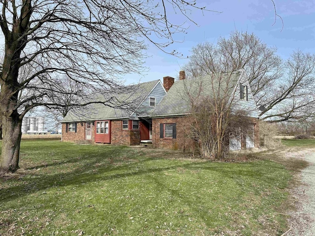 view of front of property featuring a chimney, brick siding, and a front yard