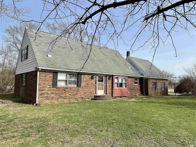 view of front of home featuring a chimney, brick siding, and a front yard