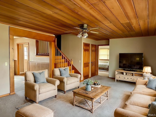 carpeted living room with stairs, a ceiling fan, and wooden ceiling