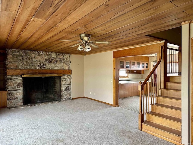 unfurnished living room with carpet flooring, stairway, ceiling fan, wood ceiling, and a fireplace