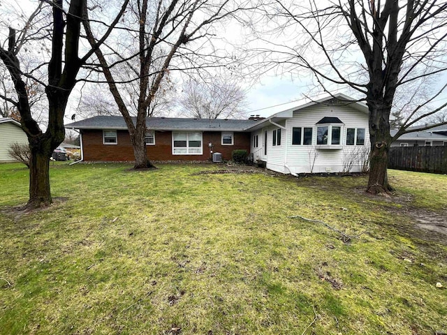 view of front of house with a front lawn, cooling unit, fence, and brick siding